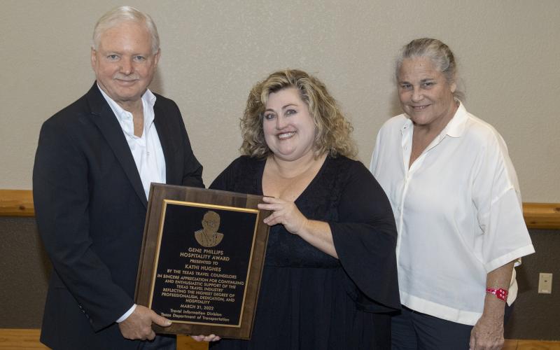 Kathi Hughes accepts her award from Bob Phillips with Phillips Entertainment and Joan Henderson, Director of TX Dot Travel Information Division.