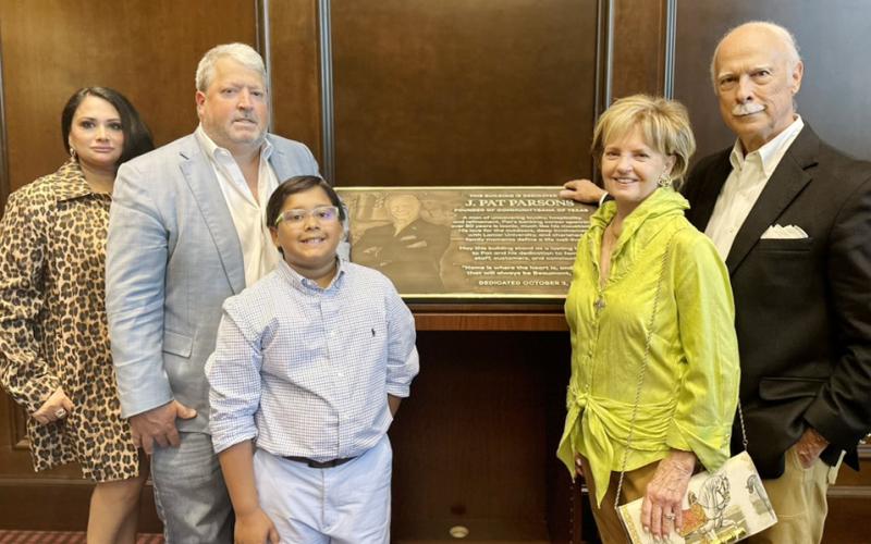 Standing aside the plaque at the  building dedication are the Parsons  family: Ayn and John Pat with son, Tripp, and Melody and Pat.