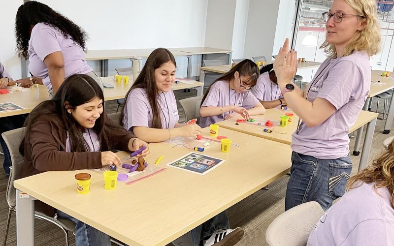 A volunteer instructs  a group of middle school girls  about electricity by building circuits from modeling clay. | Photo by Dannie Oliveaux
