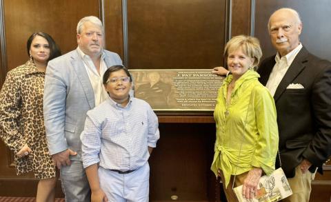 Standing aside the plaque at the  building dedication are the Parsons  family: Ayn and John Pat with son, Tripp, and Melody and Pat.