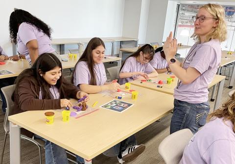 A volunteer instructs  a group of middle school girls  about electricity by building circuits from modeling clay. | Photo by Dannie Oliveaux